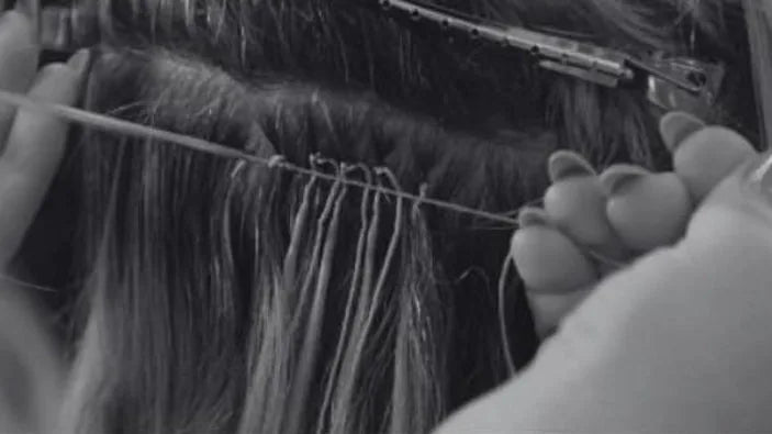 Black and white close-up of stylist installing Mago Method knot-based extensions