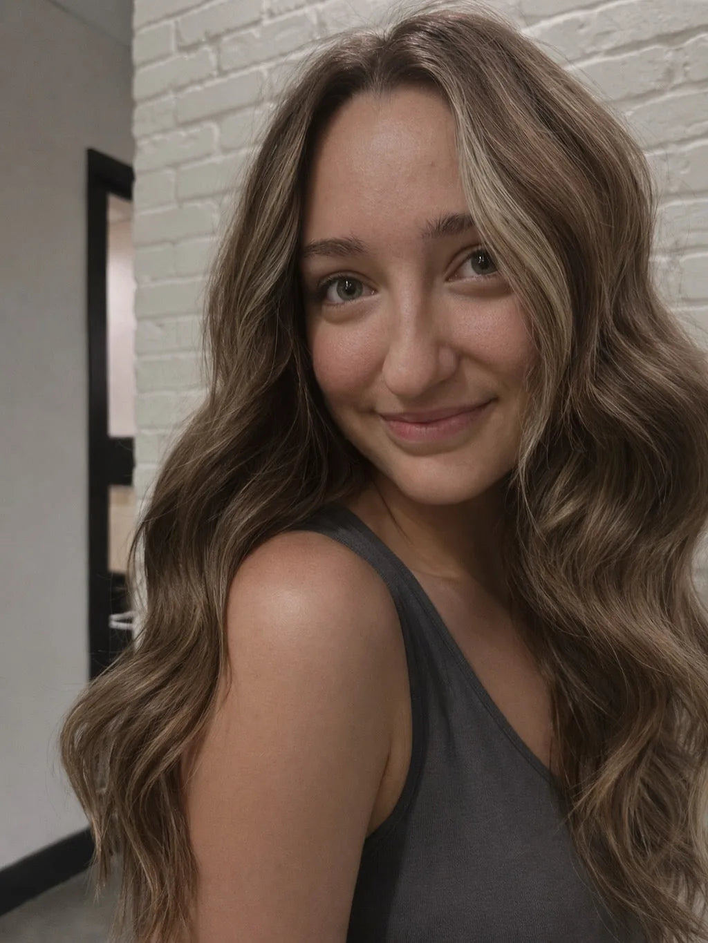 Client smiling with long wavy balayage Mago Method extensions