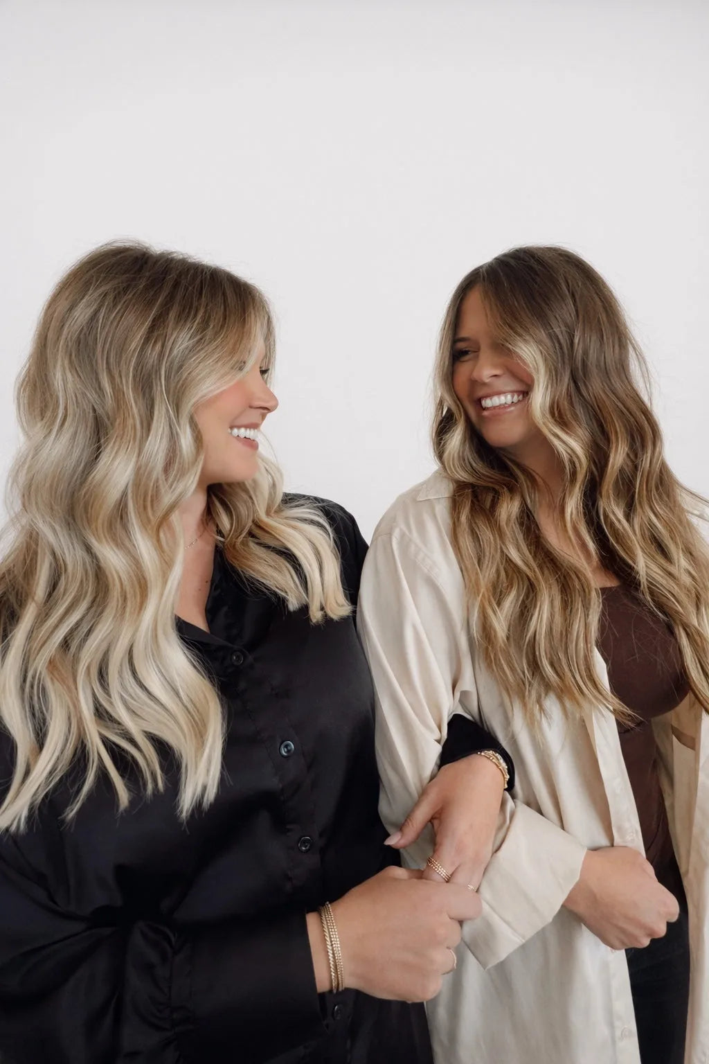 Two clients laughing with long wavy balayage Mago Method extensions
