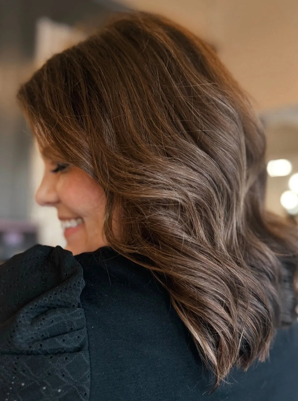 Side profile of client with brunette wavy Mago Method extensions