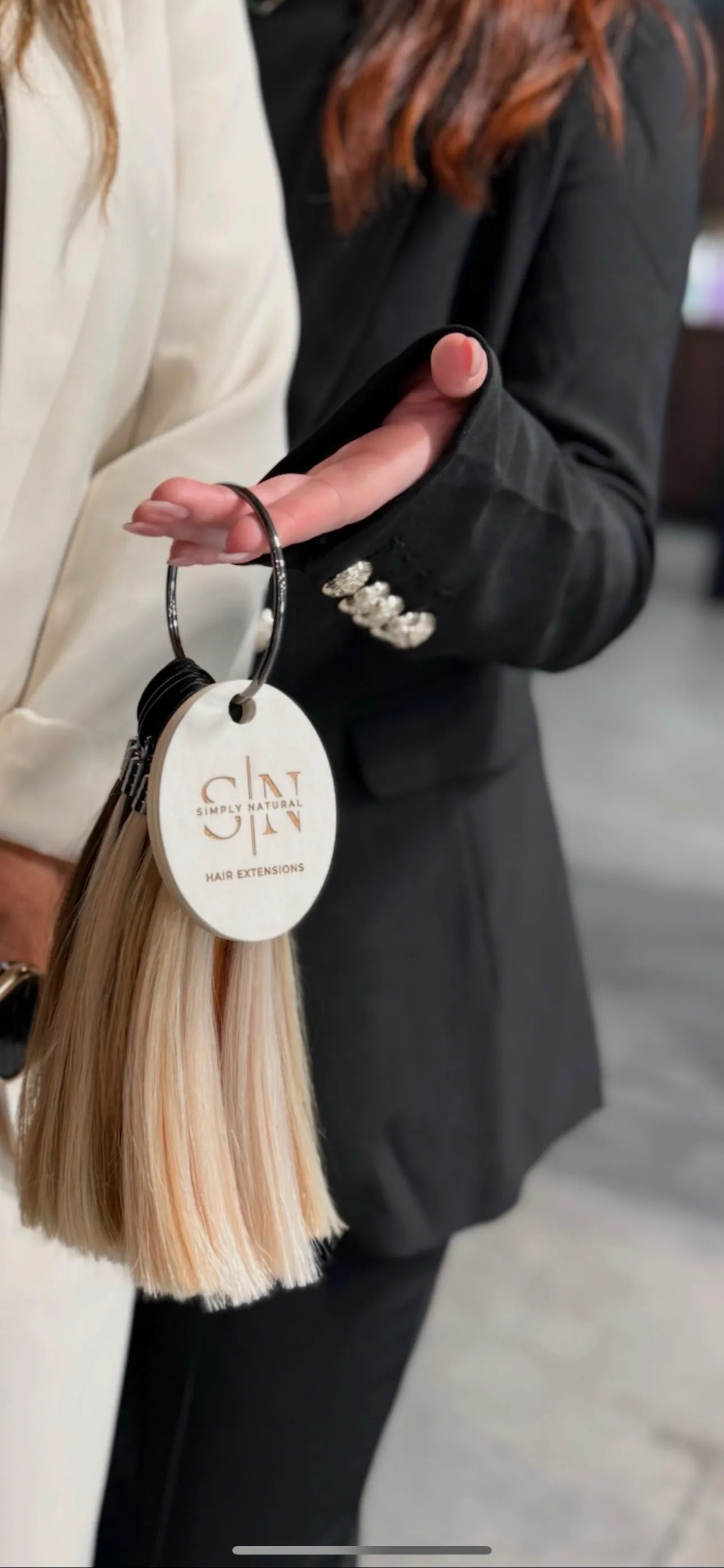 Hand holding Simply Natural color ring with blonde hair extension swatches